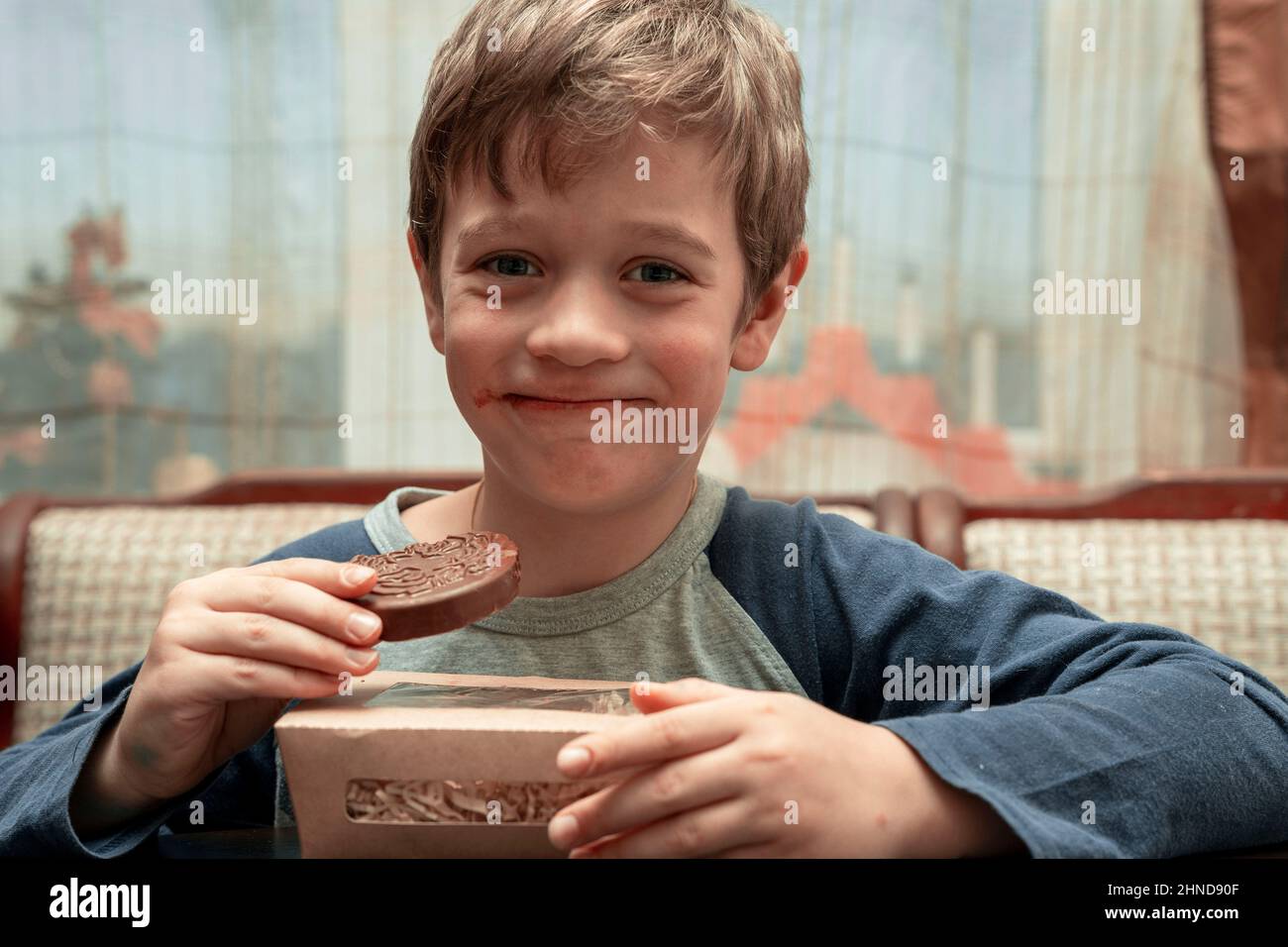funny cute Caucasian boy who eats chocolate with pleasure. chocolate covered face Stock Photo
