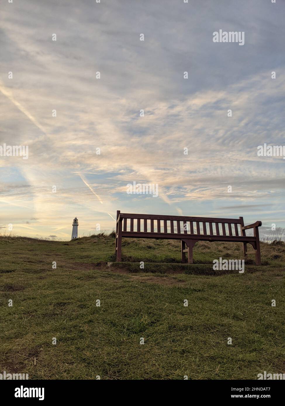 A wooden bench against a beautiful sunset sky Stock Photo