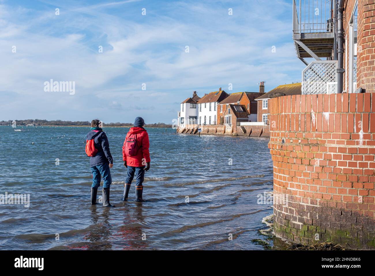 Bosham village, view of the pretty coastal tourist or visitor attraction in West Sussex, England, UK. Two visitors walkers at high tide. Stock Photo