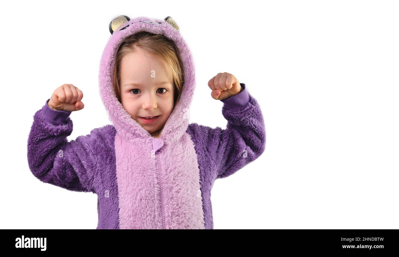 preschool little girl shows strong strength tensing muscles in purple pajamas Stock Photo