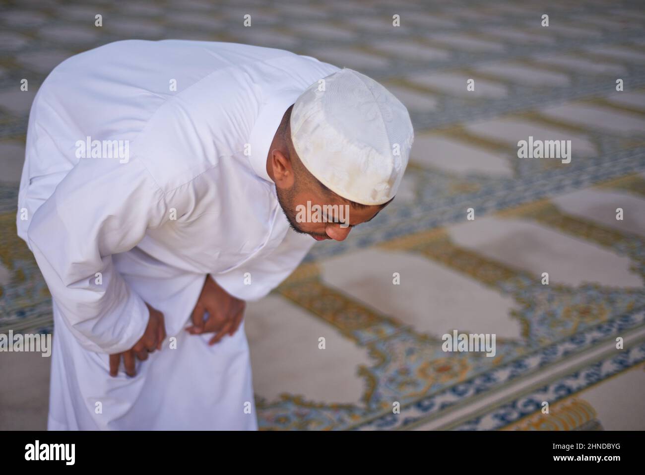 An overhead view of a young Muslim man bowing during prayers at a mosque Stock Photo