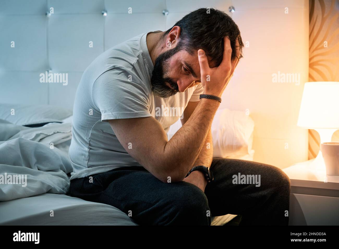 person with some kind of problem sitting on the bed and shaking their head while stirring their hair Stock Photo