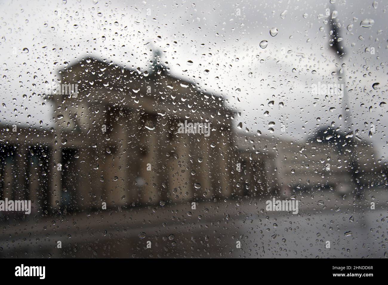 Berlin, Germany. 16th Feb, 2022. Raindrops prevent a direct view of the Brandenburg Gate through the window of a bus, with increasing rain showers and gusts of wind. According to meteorologists, storms and gale-force winds with wind speeds of up to 120 km/h are expected in the coming night and for the next few days. Credit: Wolfgang Kumm/dpa/Alamy Live News Stock Photo