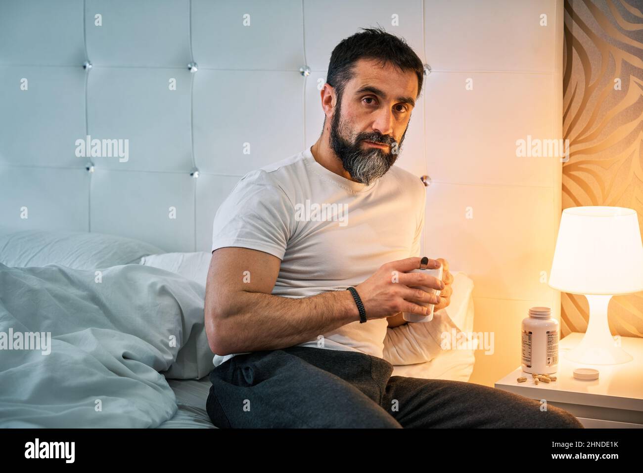 person with some kind of problem sitting on the bed enjoying a cup of coffee or infusion. Stock Photo