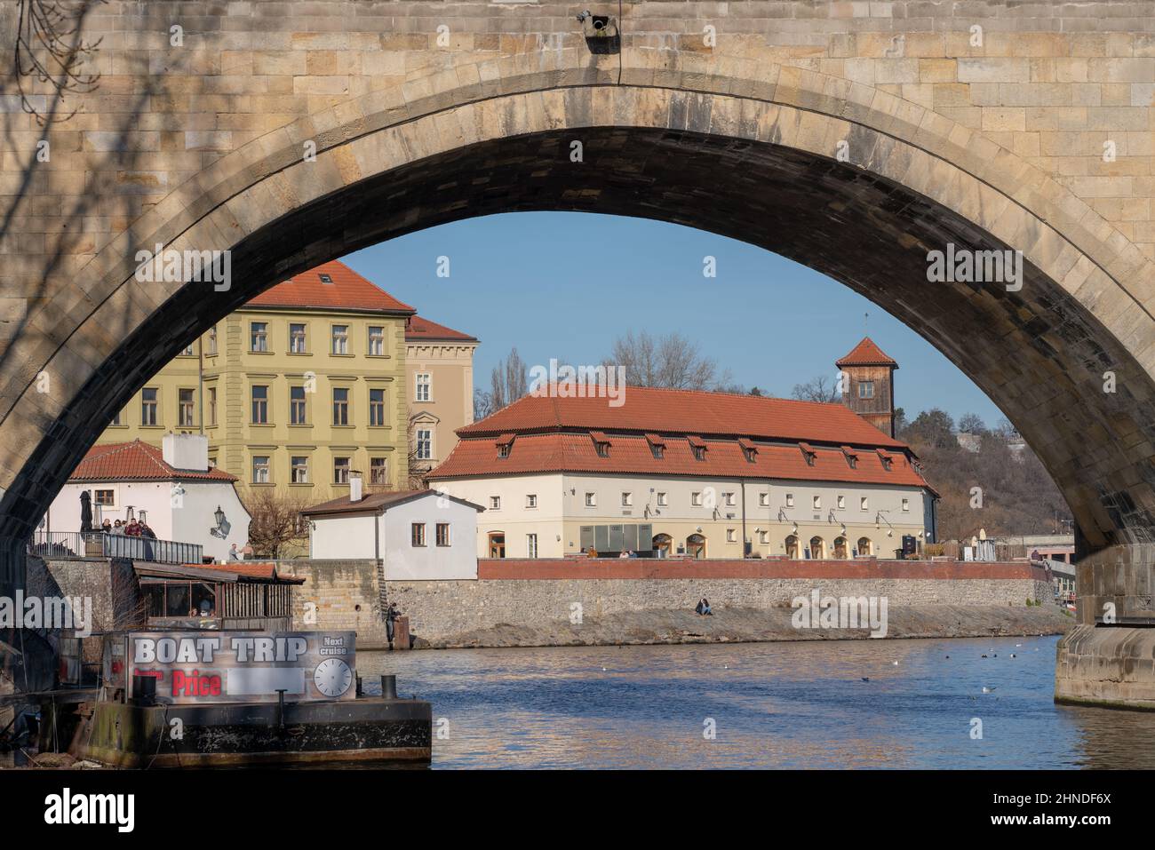 A look through an arch of Charles Bridge in Prague towards former Herget's Brickworks ('Hergetova cihelna'), a cultural centre, restaurant and museum. Stock Photo