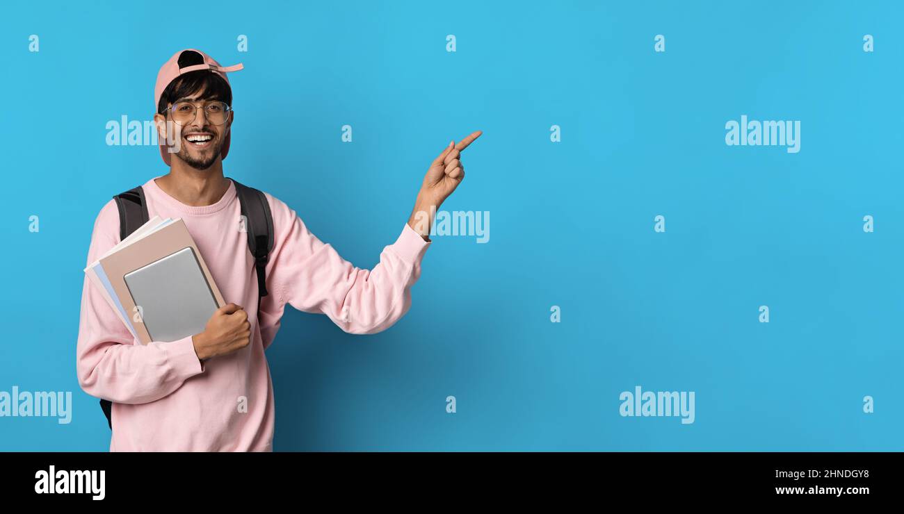 Cheerful middle eastern guy student pointing at copy space Stock Photo