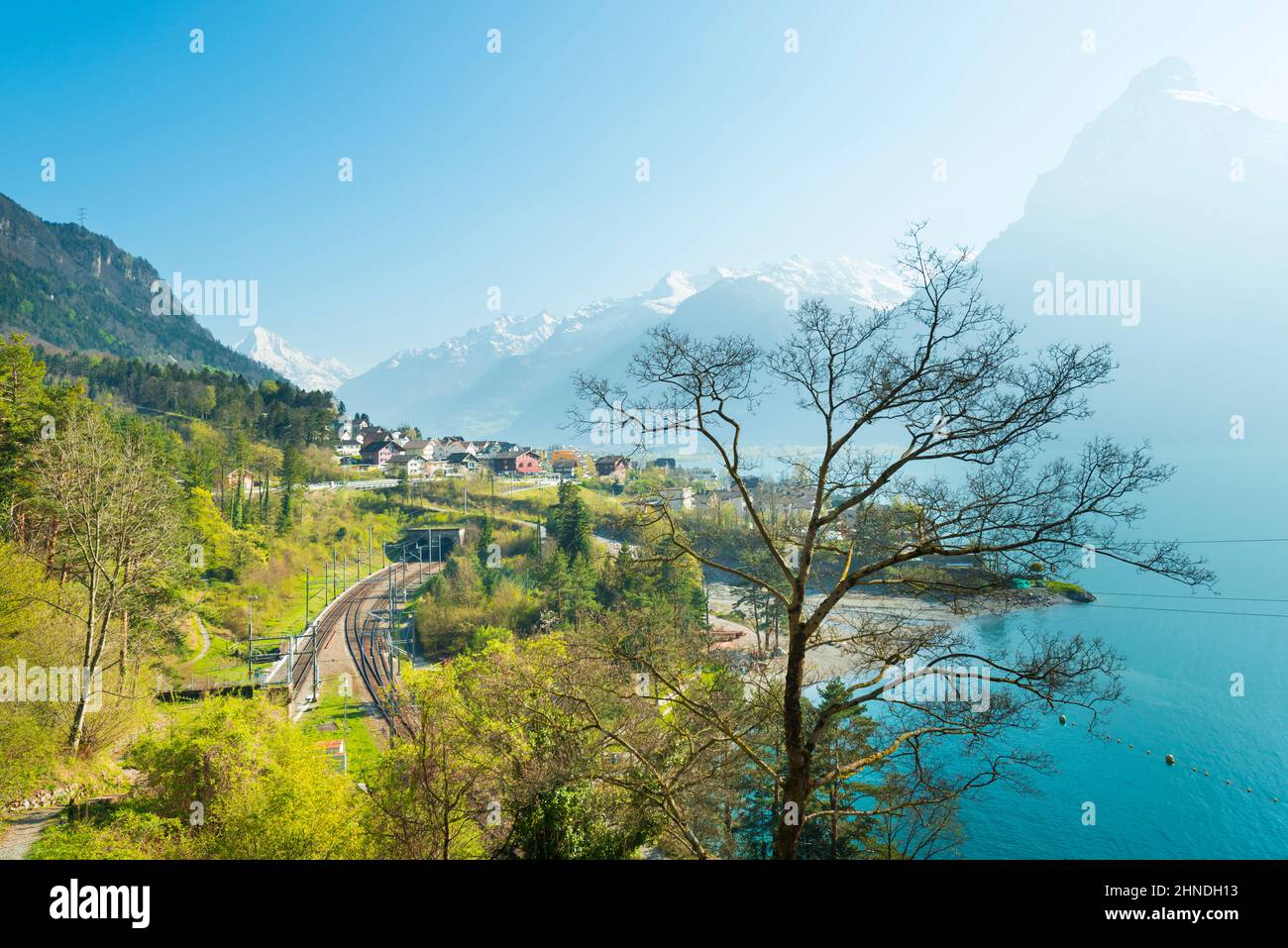 View of the small town in the Alps mountains. Traditional houses. Railway along Lake Lucerne. Canton of Uri. Stock Photo