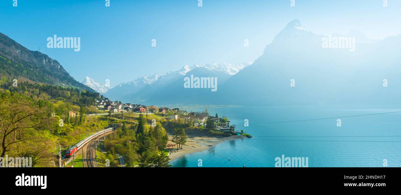 View of the small town in the Alps mountains. Traditional houses. Railway along Lake Lucerne. Canton of Uri. Stock Photo