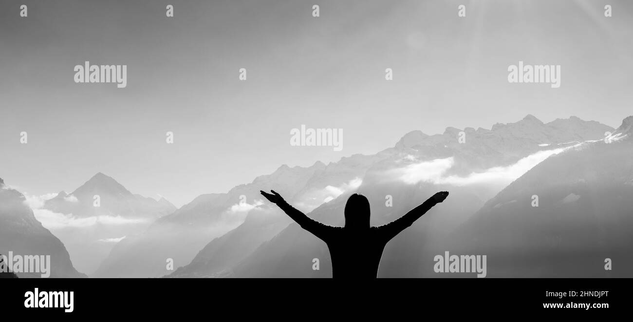 Female figure in the background of a mountain range. Sun rays. Stock Photo