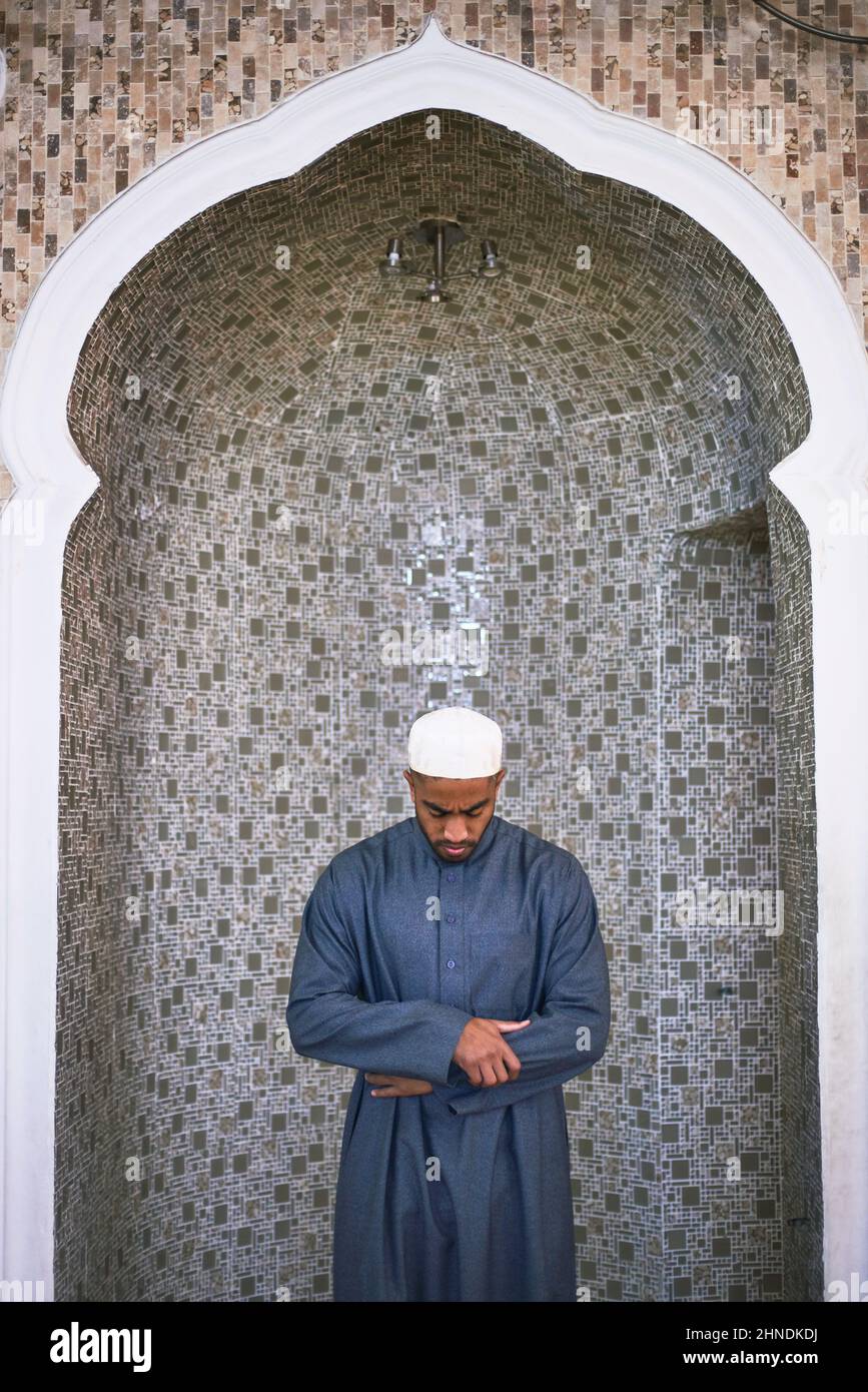 A young Muslim man stands with his head bowed in prayer Stock Photo