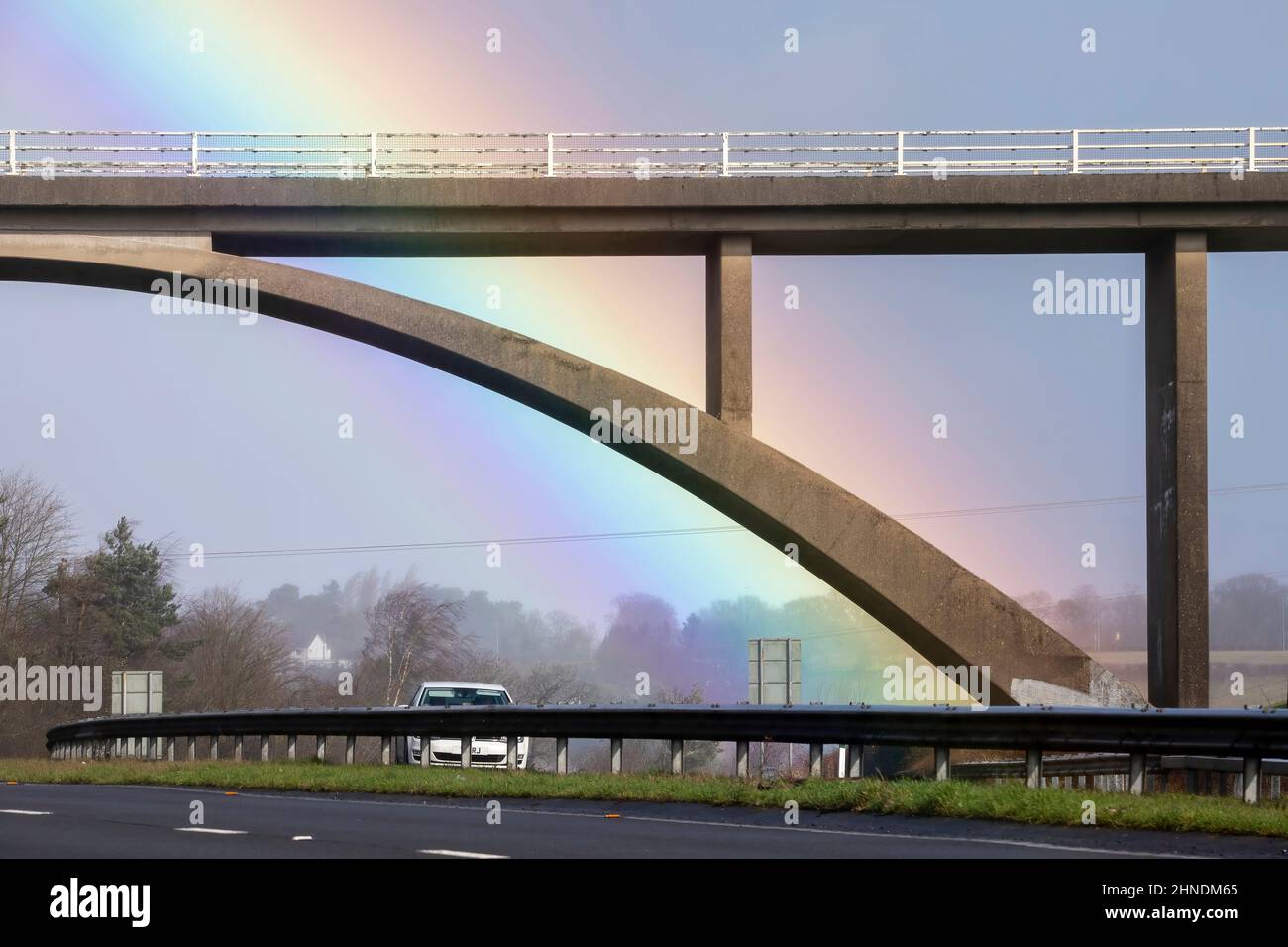 A beautiful Rainbow falling behind a highway bridge Stock Photo