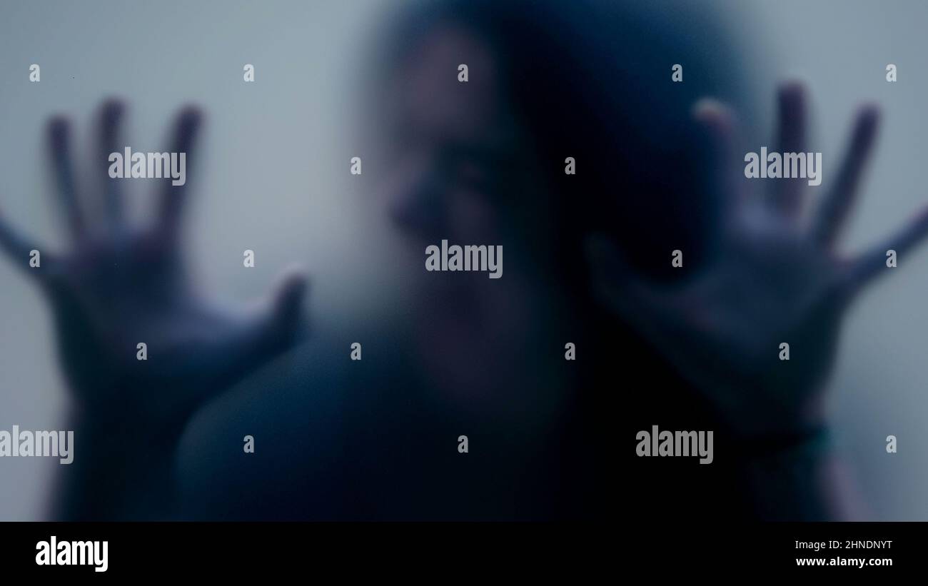 Defocused shot of person trapped in emotional problems behind glass ...