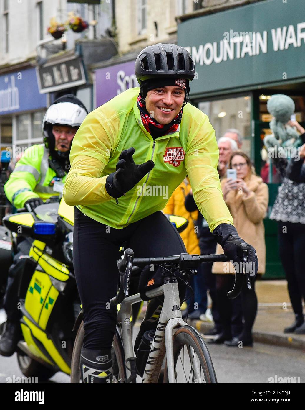 Bridport, Dorset, UK.  16th February 2022.  Olympic gold medalists Tom Daley OBE is cheered on by people lining the street as he rides through Bridport in Dorset on day 3 of his Comic Relief Hell of a Homecoming challenge from the Queen Elizabeth Olympic Park in Stratford to his hometown of Plymouth in Devon.  On this leg he is cycling 130 miles from Southampton to Bovey Castle on Dartmoor in Devon.  Picture Credit: Graham Hunt/Alamy Live News Stock Photo