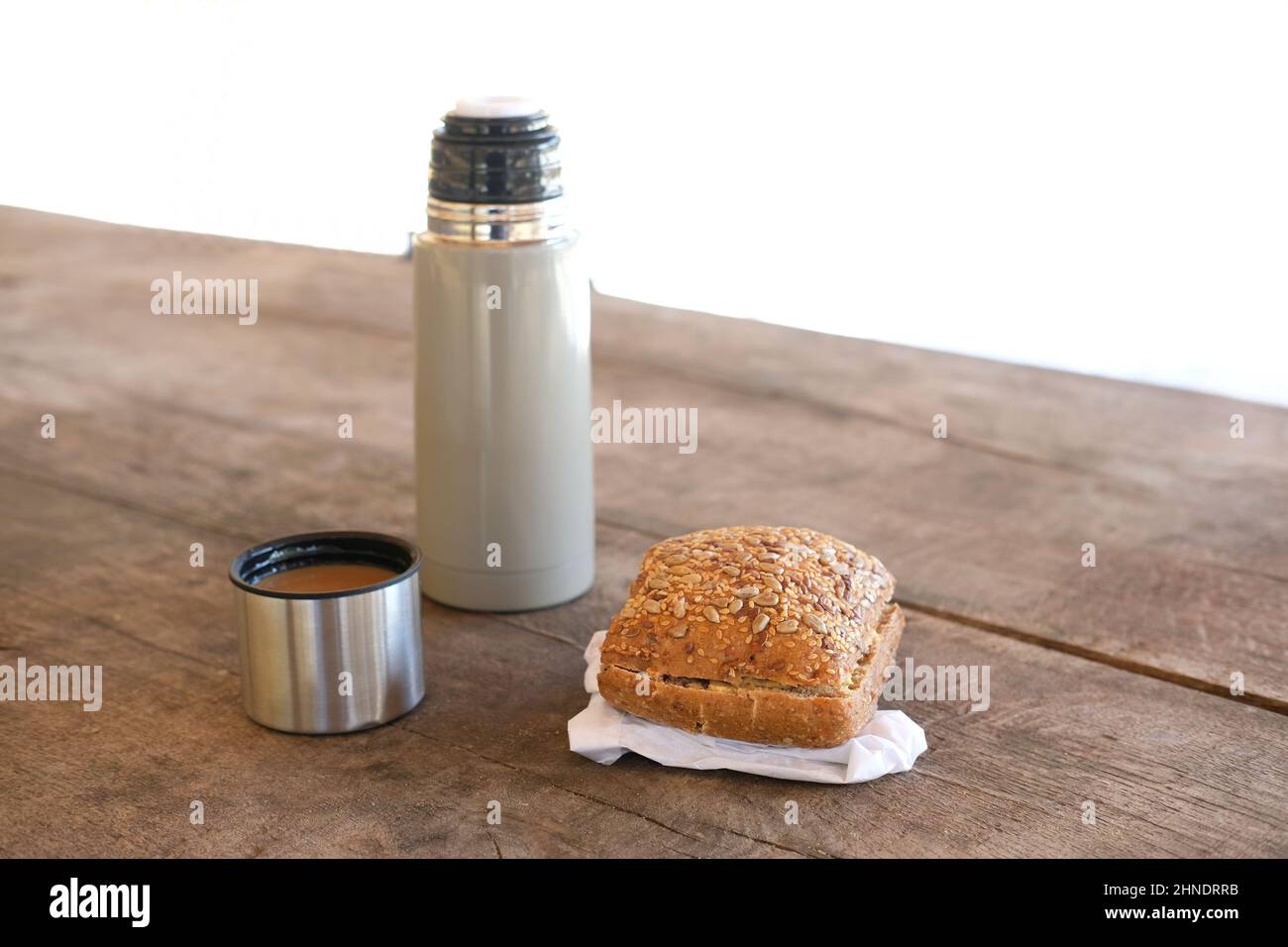 https://c8.alamy.com/comp/2HNDRRB/outdoor-lunch-when-hiking-in-forest-hot-white-coffee-in-thermos-flask-and-homemade-sandwich-on-wooden-table-2HNDRRB.jpg