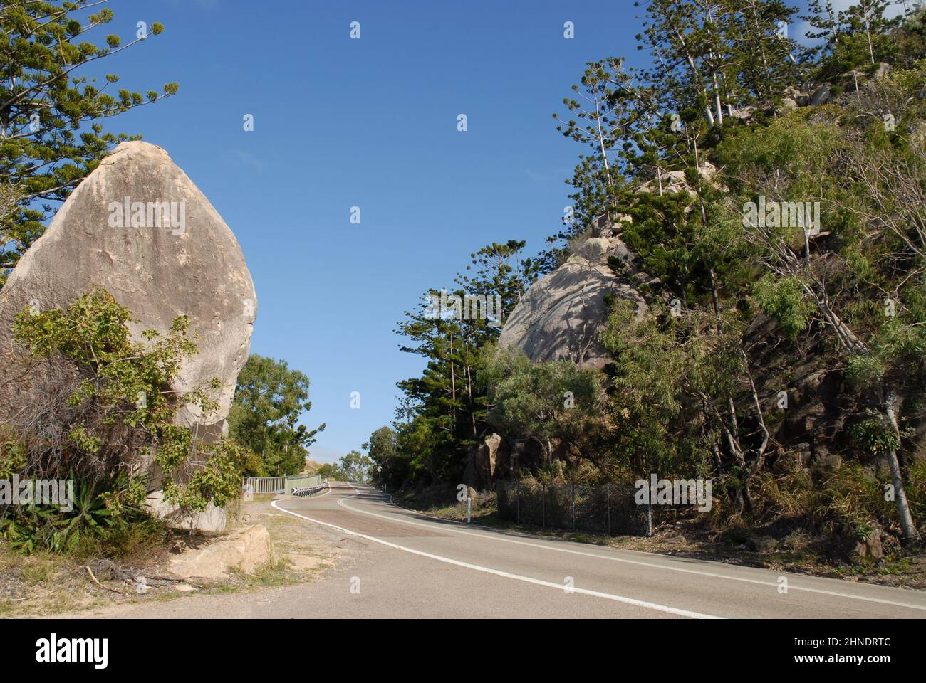 The road on Magnetic Island, with granite boulders, Hoop pines and eucalyptus trees, Queensland, Australia Stock Photo