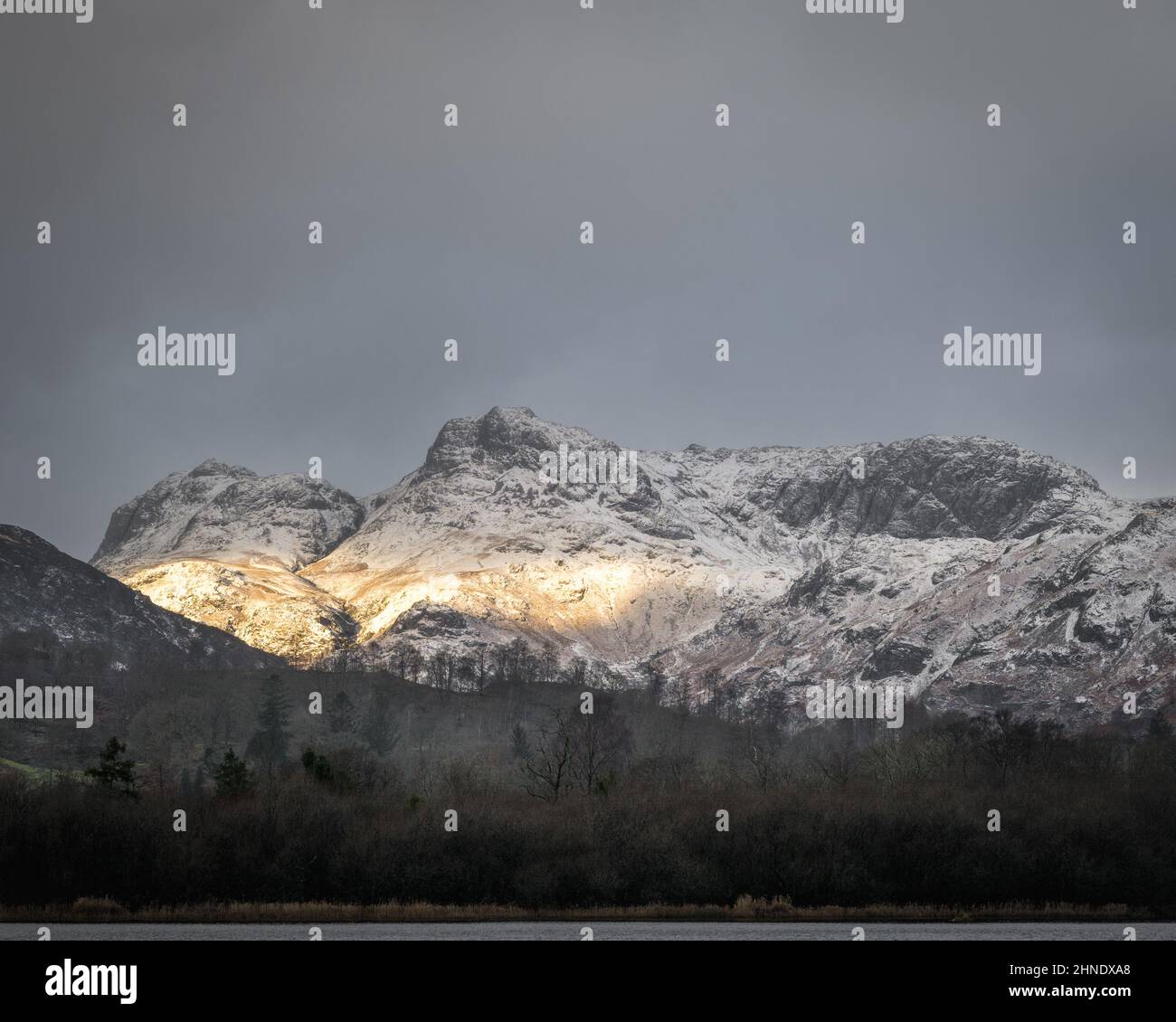 Low winter light illuminates the snow-covered Langdale Pikes Stock Photo