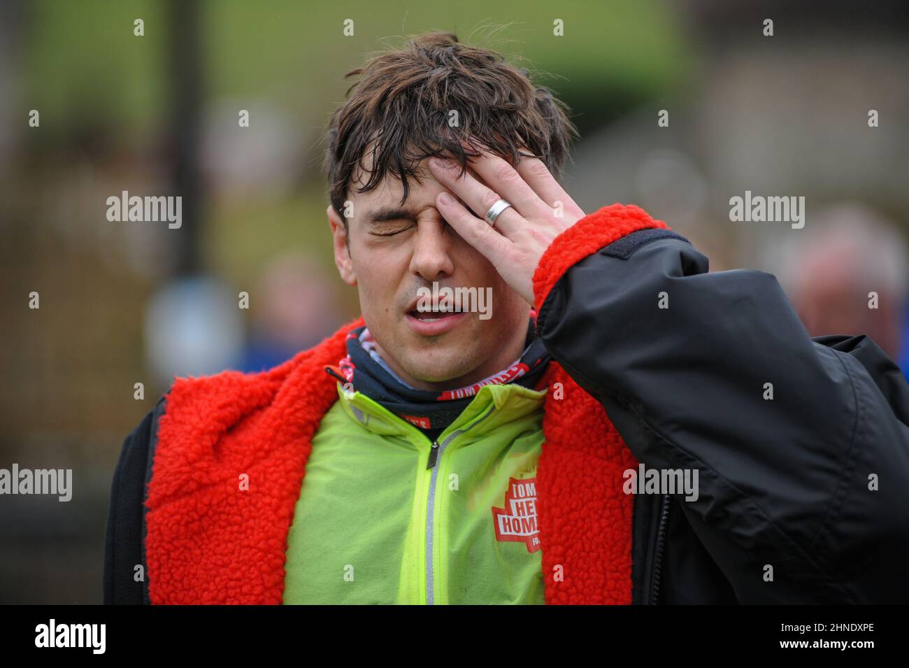 Winterbourne Abbas, Dorset, UK. 16th February 2022. Olympic gold medalists Tom Daley feels the strain after 7 hours of riding on day 3 of his Comic Relief Hell of a Homecoming Challenge from the Queen Elizabeth Olympic Park in London to his hometown of Plymouth in Devon. On this leg he is cycling 130 miles from Southampton to Bovey Castle on Dartmoor in Devon. Credit: David Partridge / Alamy Live News Stock Photo