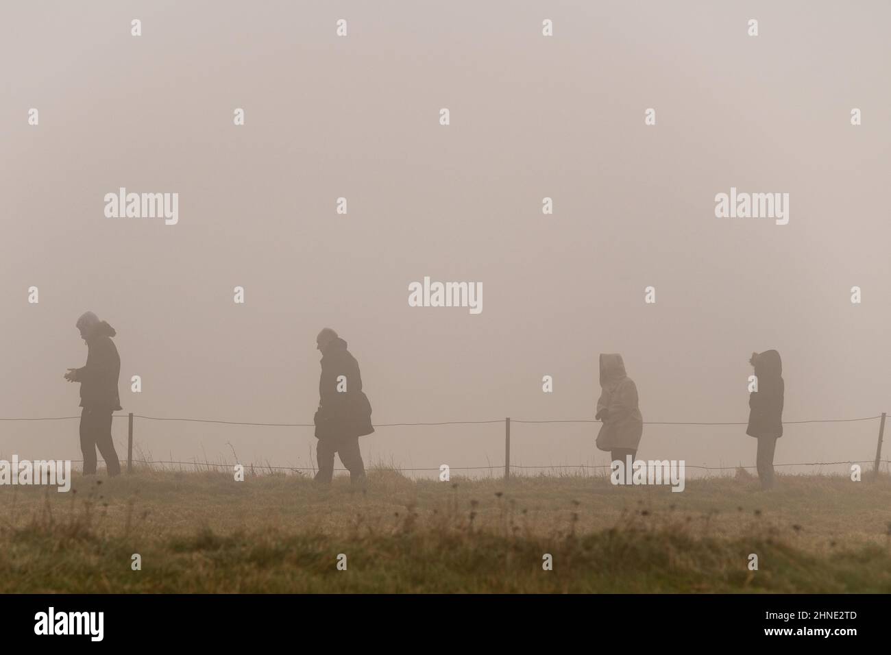 16th February, 2022. 16th February, 2022. UK WEATHER - a family stand near the cliff edge at Beachy Head in thick fog and gale force winds, East Sussex, UK Stock Photo
