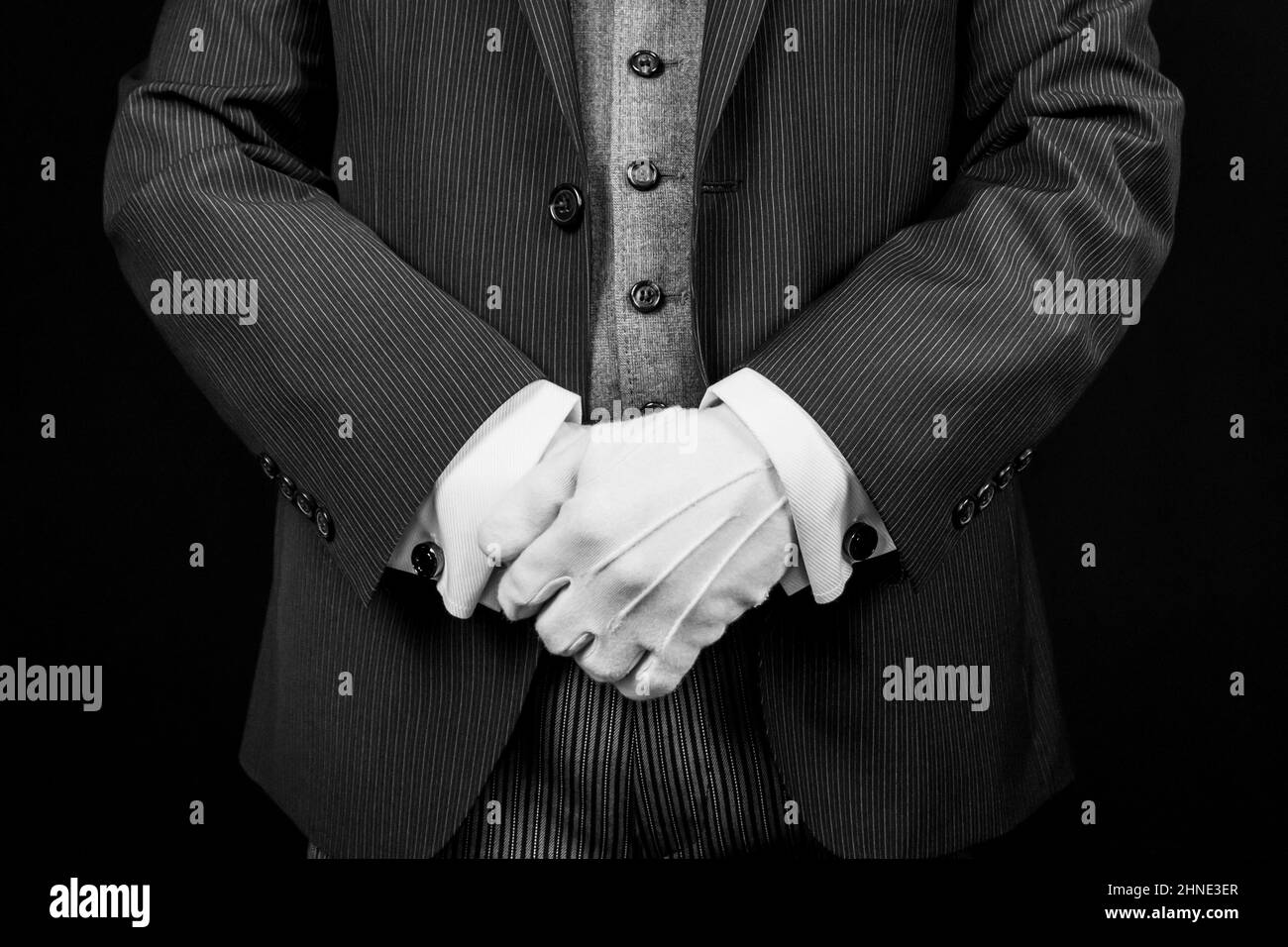 Butler in Dark Suit and White Gloves Standing at Respectful Attention. Concept of Service Industry and Professional Hospitality. Stock Photo