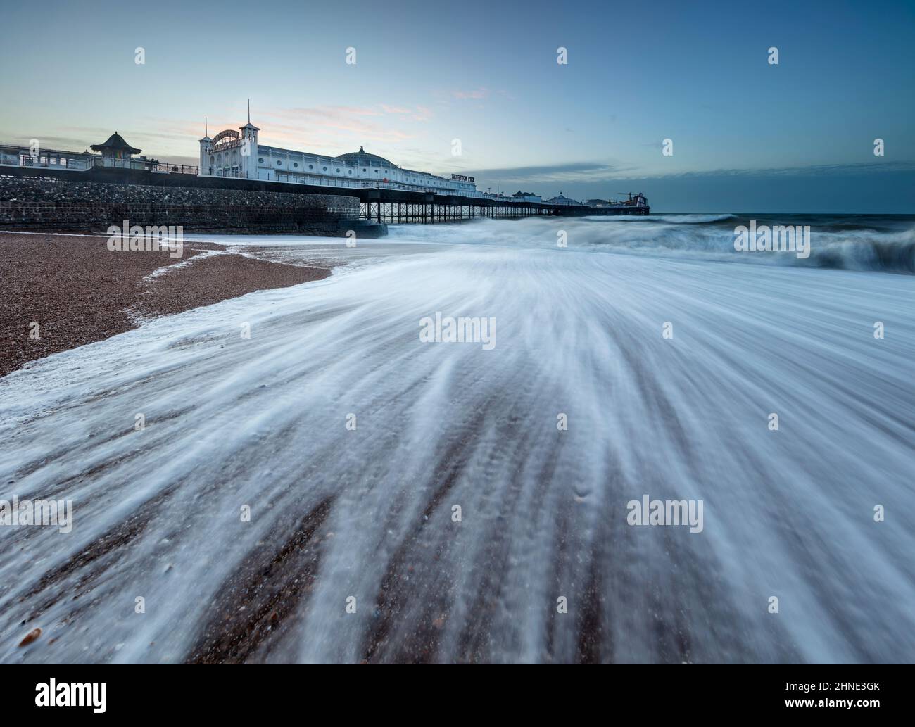 Brighton Pier at dawn with stormy waves breaking on shingle beach, Brighton, East Sussex, England, United Kingdom, Europe Stock Photo