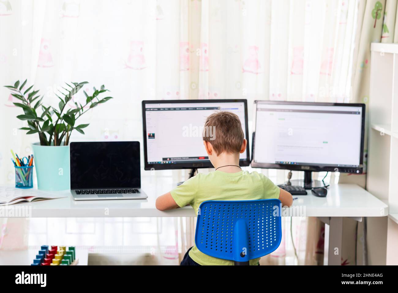Little young school boy working at home with a laptop and class notes ...