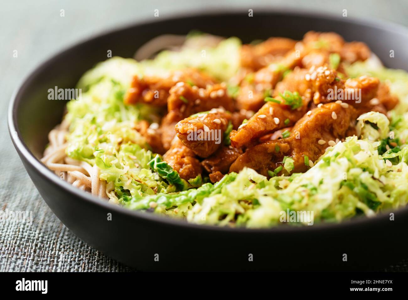 Spicy soy curls on shredded savoy cabbage, served with buckwheat noodles. Stock Photo