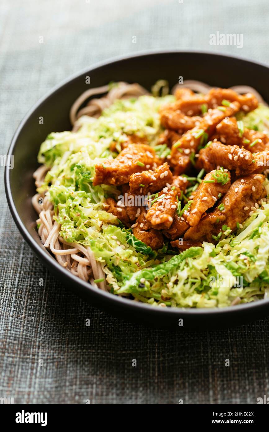 Spicy soy curls on shredded savoy cabbage, served with buckwheat noodles. Stock Photo