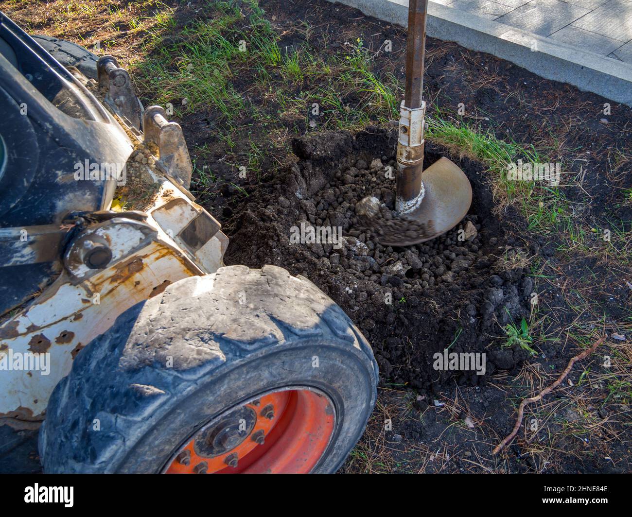 Drilling holes in the ground with a tractor with auger drill Stock