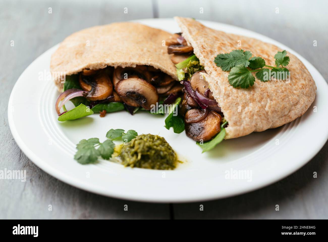 Pita breads filled with sauteed mushrooms and onions with winter purslane and corn salad, served with zhoug. Stock Photo