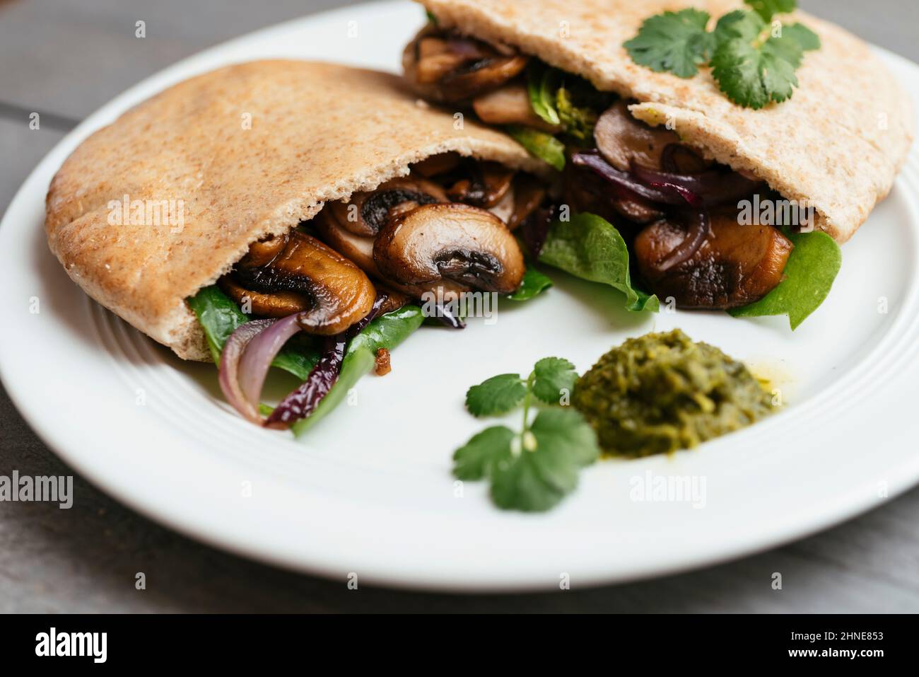 Pita breads filled with sauteed mushrooms and onions with winter purslane and corn salad, served with zhoug. Stock Photo