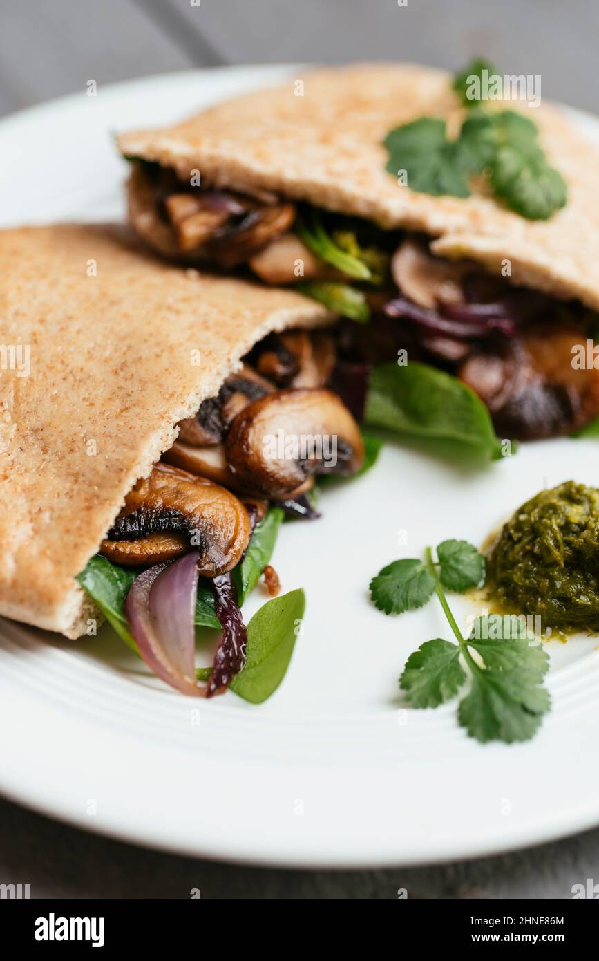 Pita breads filled with sauteed mushrooms and onions with winter purslane and corn salad, served with zhoug. Stock Photo