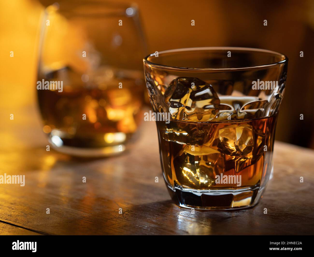 Glass of whisky on the rocks on a wooden bar top Stock Photo