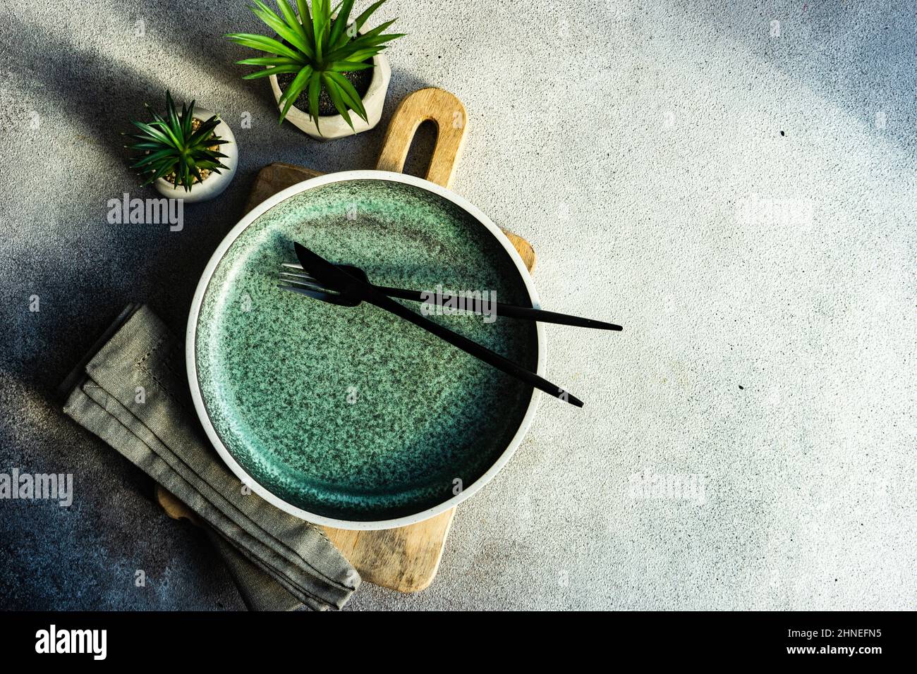 Minimalistic table setting on a chopping board with two houseplants Stock Photo