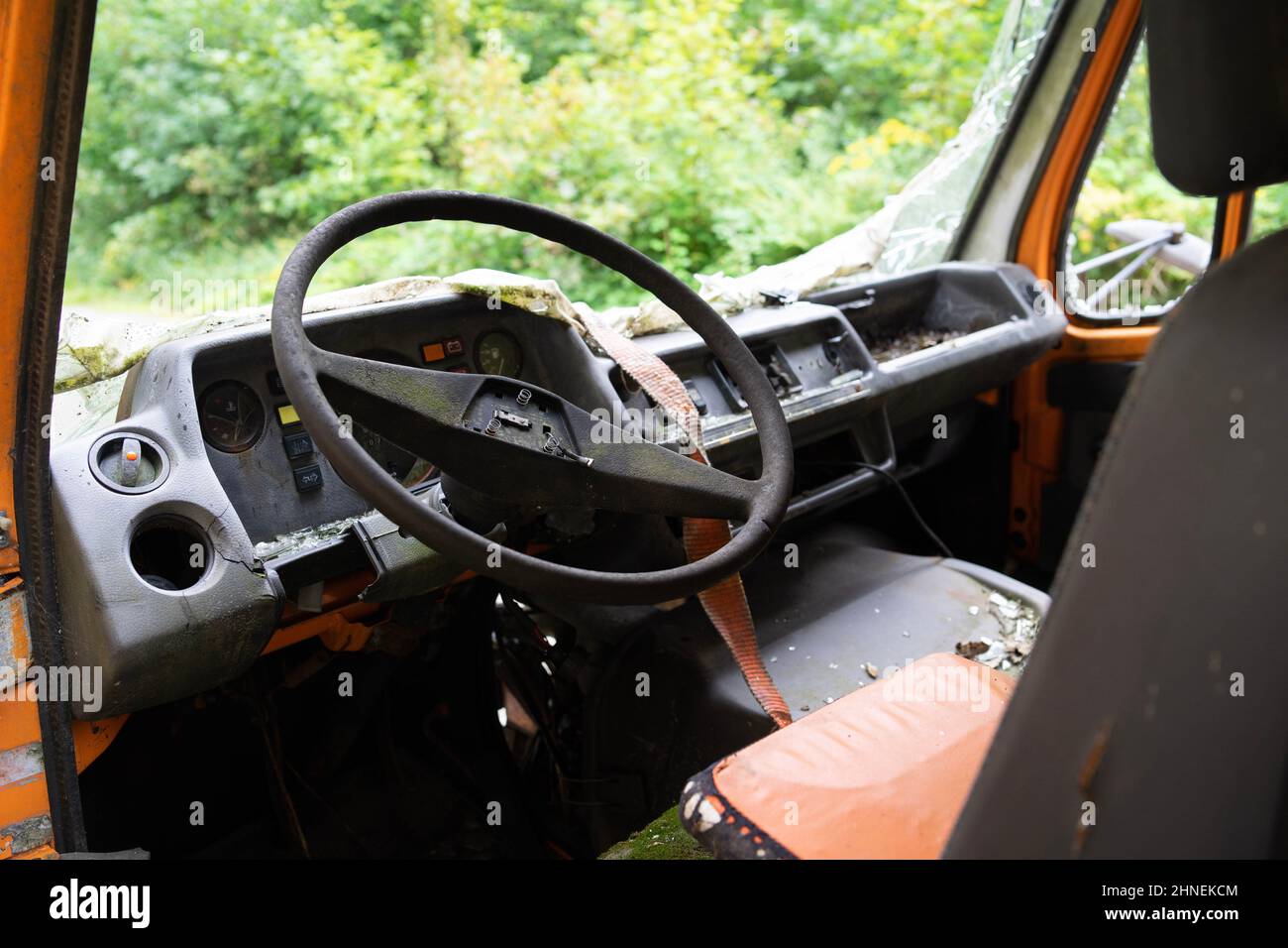 broken steering wheel of an old orange delivery van in front of an old abandoned sanatorium, Germany Stock Photo