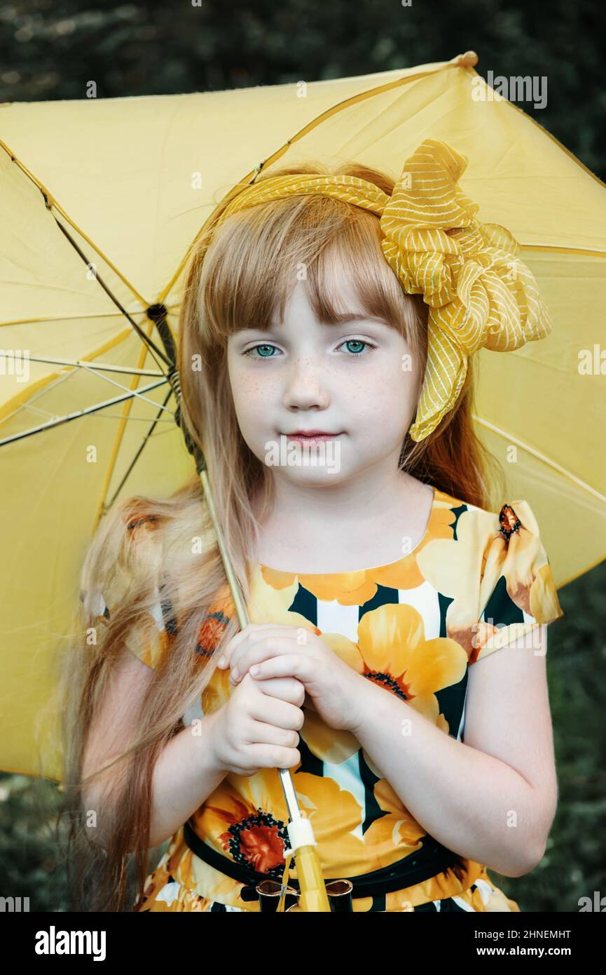 beautiful redhaired girl with yellow bow and yellow umbrella. An 11