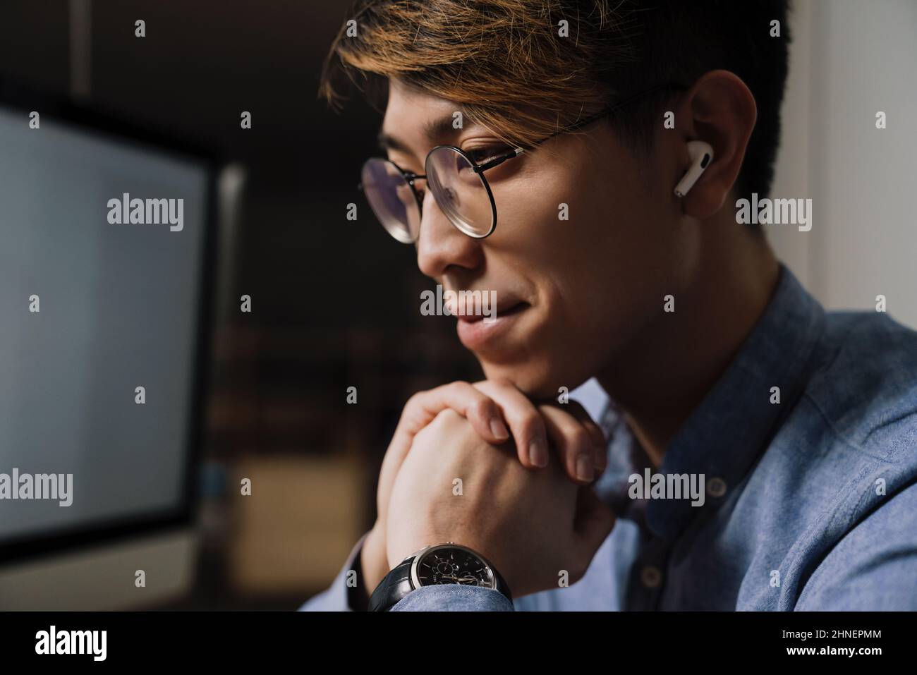 Pleased asian guy in earphones working with computer in office Stock ...