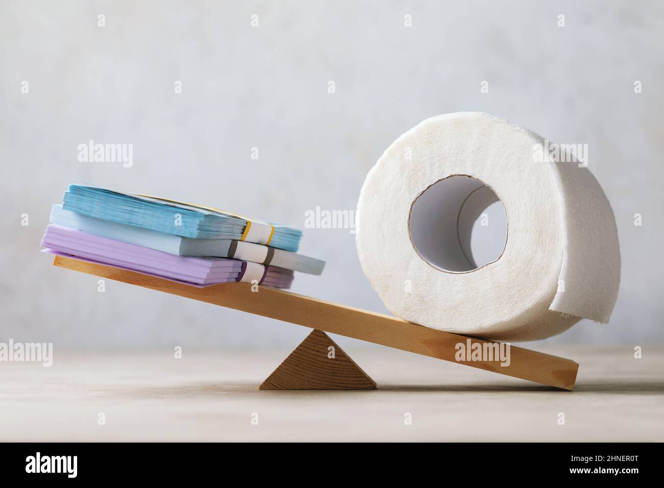 Roll of toilet paper outweighed money on scales, bloated economy concept, money is paper Stock Photo