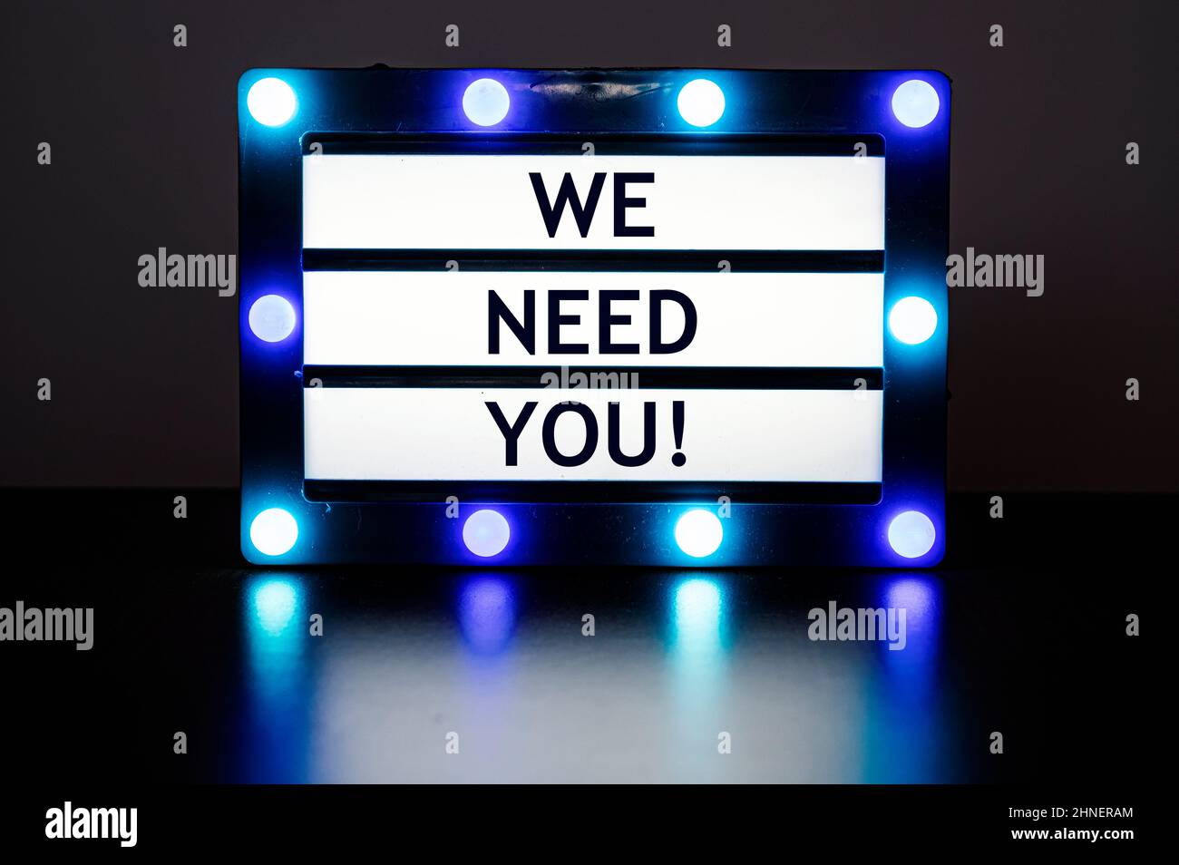 Lightbox with blue lights in dark room with words - we need you! Stock Photo