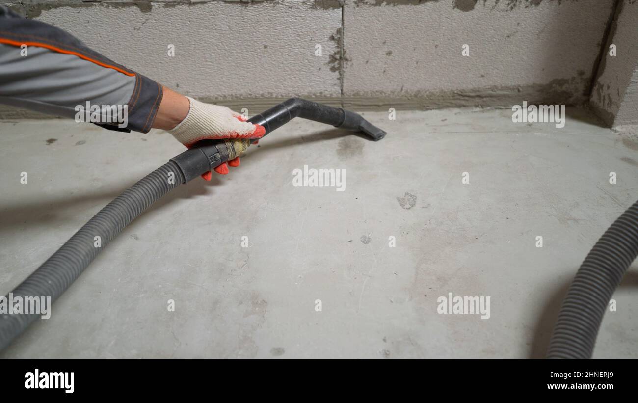 A worker vacuums the floor with an industrial vacuum cleaner. Preparing