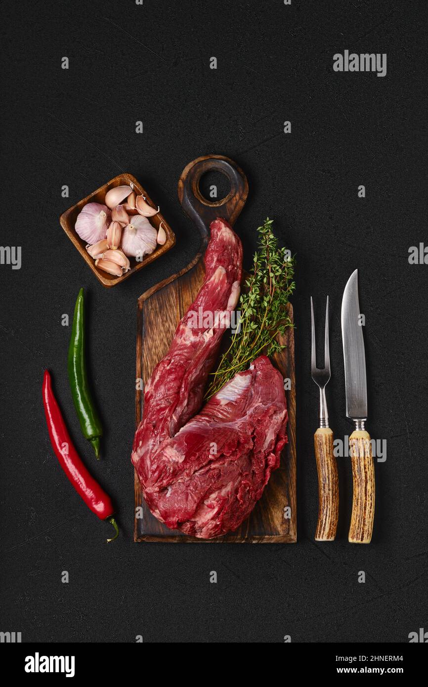 Raw beef whole tenderloin with herbs and spice on black background Stock Photo