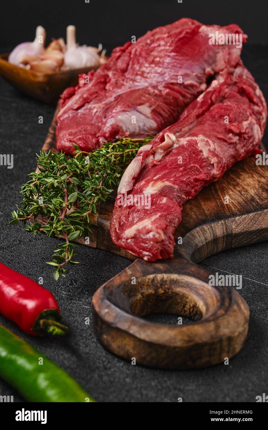 Closeup view of raw beef whole tenderloin with herbs and spice on black background Stock Photo