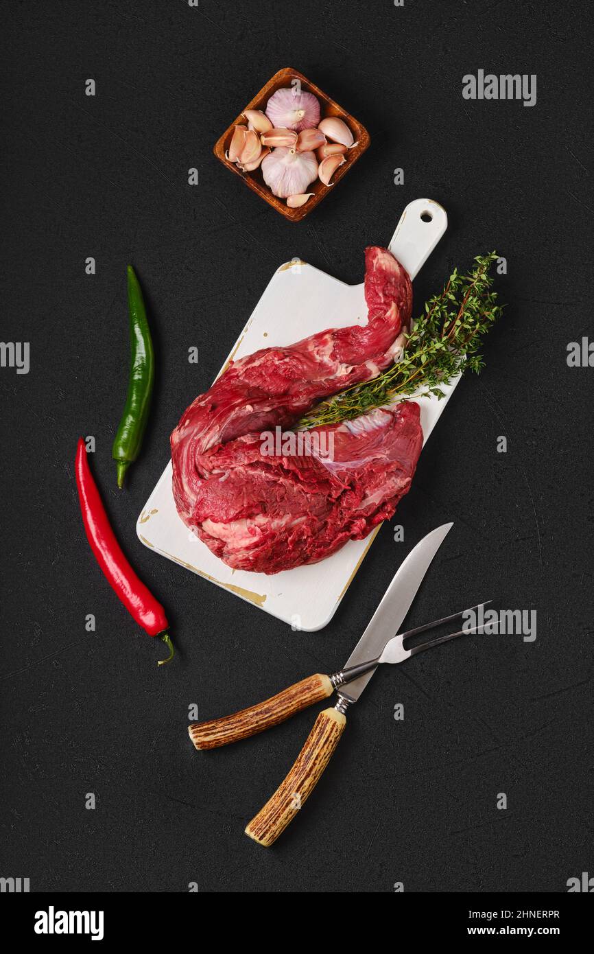 Composition with raw beef whole tenderloin on black background Stock Photo