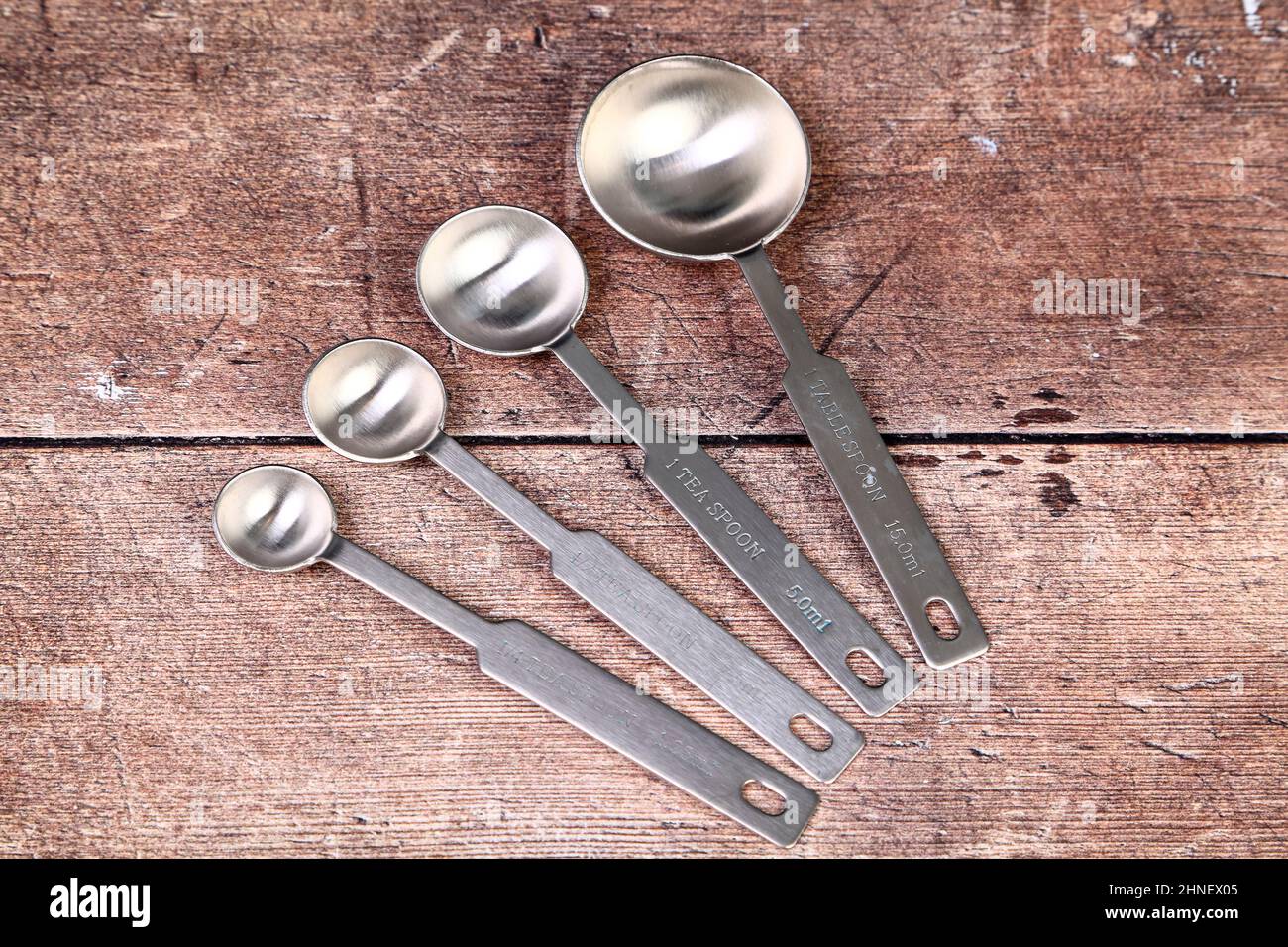 https://c8.alamy.com/comp/2HNEX05/wooden-kitchen-table-with-a-set-of-stainless-steel-measuring-spoons-baking-concept-2HNEX05.jpg