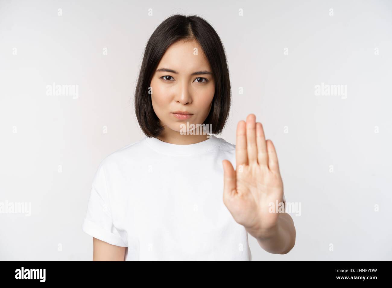 Image of asian girl showing stop, prohibit smth, extend one arm to show