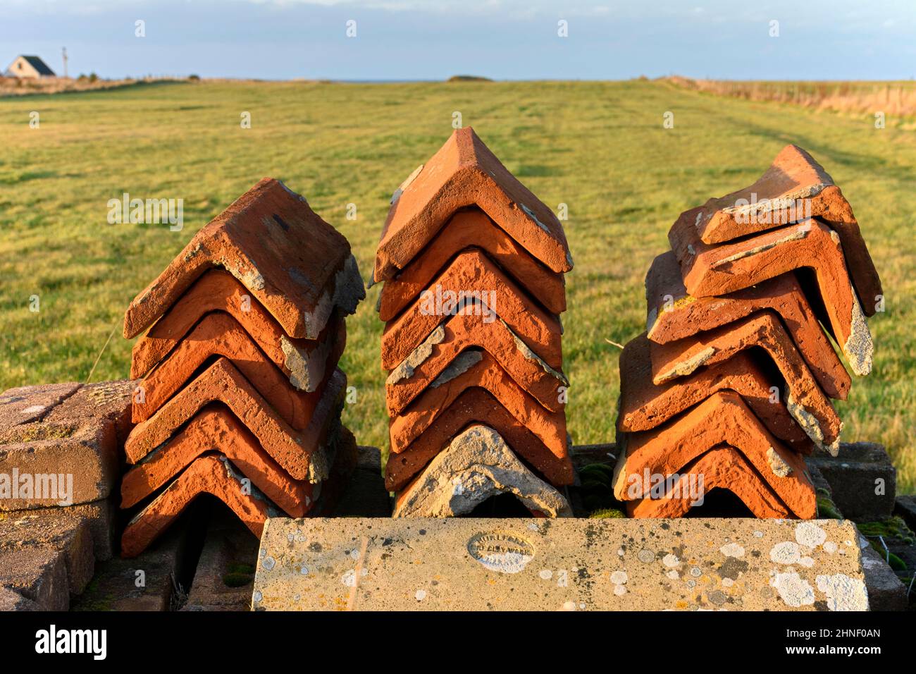 Three stacks of roof ridge tiles at the edge of a road near the village of Scarfskerry, Caithness, Scotland, UK Stock Photo