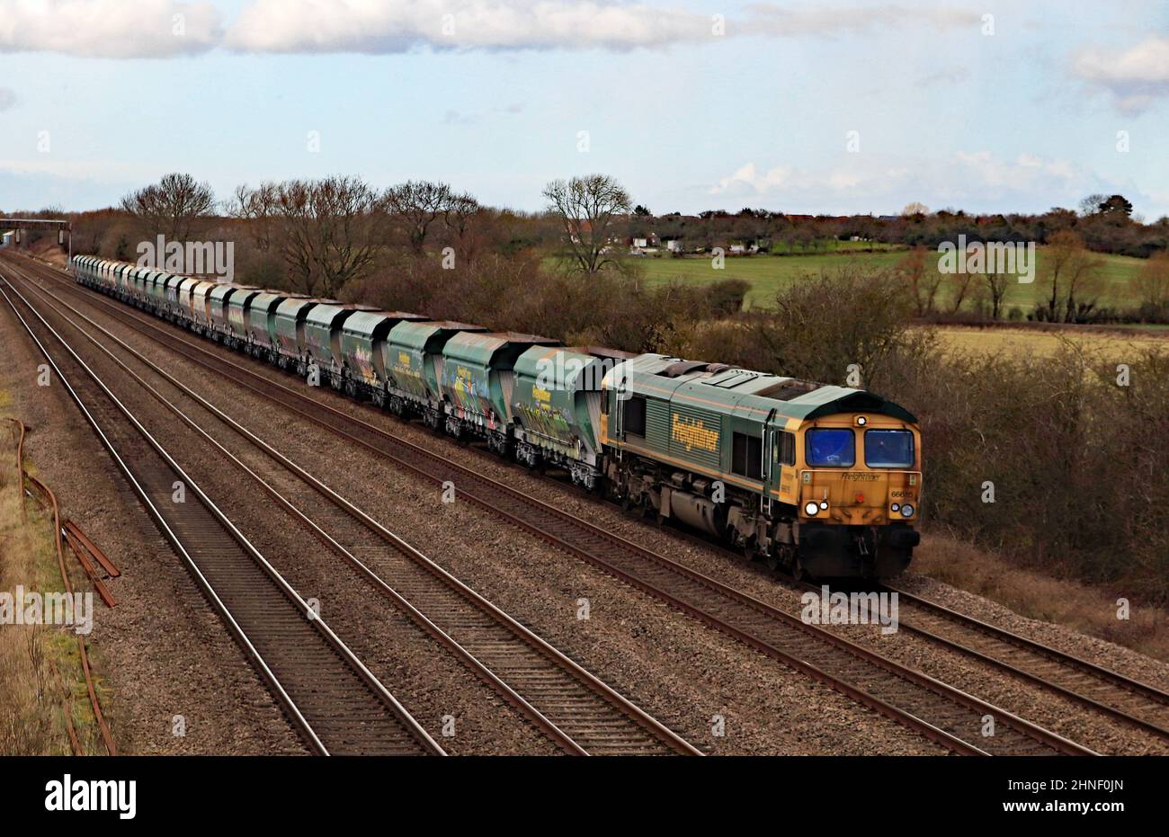 Work stained Freightliner diesel locomotive’s 66615 haul’s a train of loaded stone wagons along the Midland main line on the way to Radlett. Stock Photo