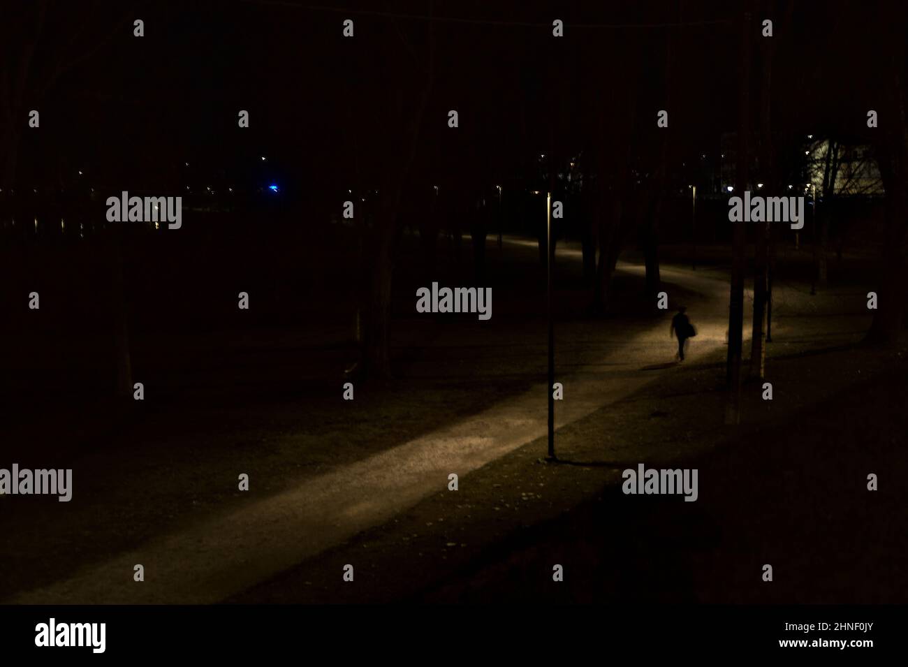 Gravel path lit by street lamps in a park at night seen from above ...