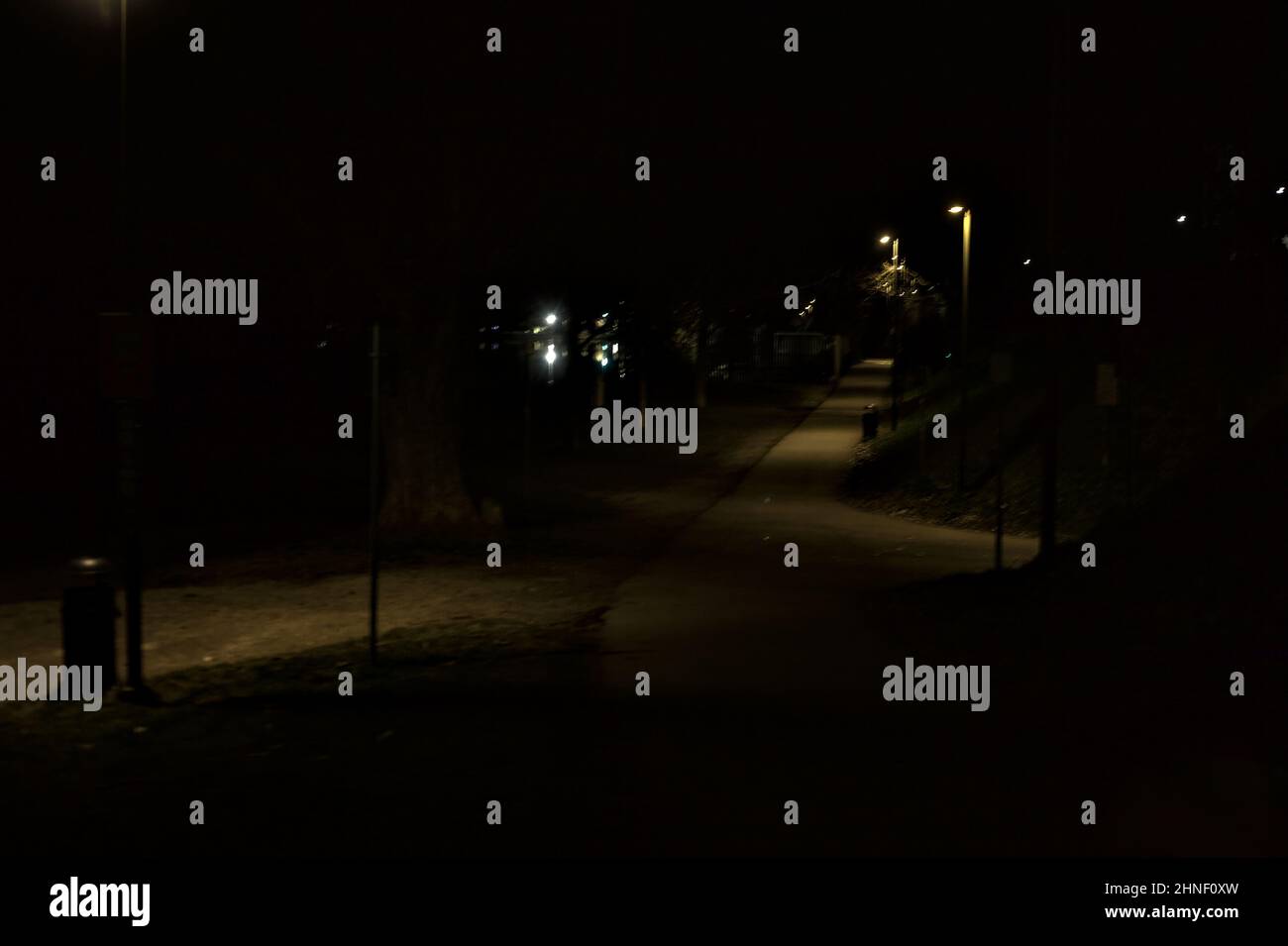 Gravel path lit by street lamps in a park at night seen from above ...