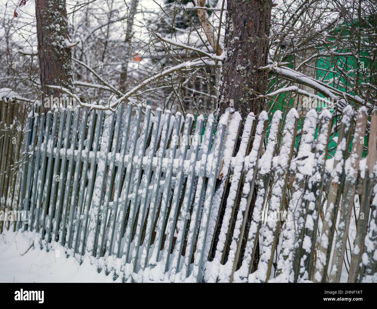Old wooden fence tilted from the snow, winter scene Stock Photo - Alamy