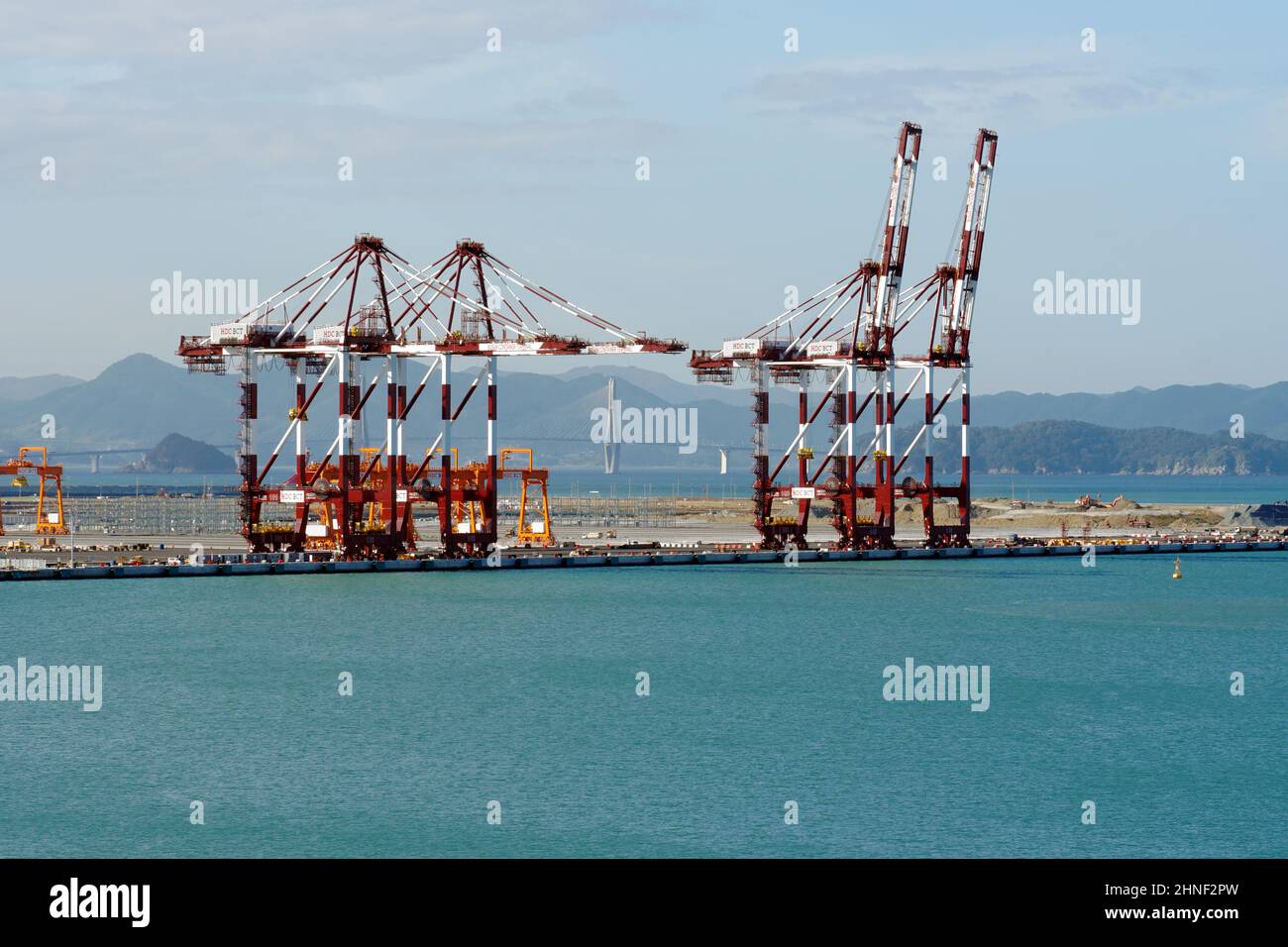 Red gantry cranes with white stripes in container terminal under construction in Busan New Port. Stock Photo
